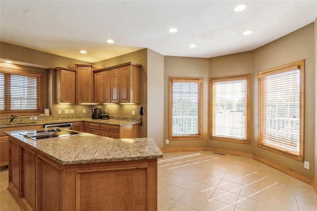 kitchen featuring stainless steel cooktop, sink, light stone countertops, a center island, and light tile patterned floors