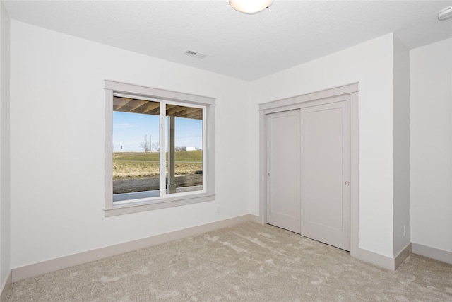 unfurnished bedroom with carpet floors, a closet, visible vents, and baseboards