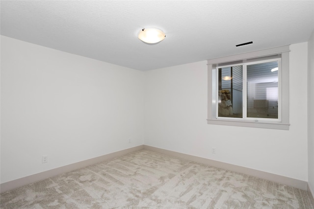 unfurnished room with carpet, baseboards, and a textured ceiling