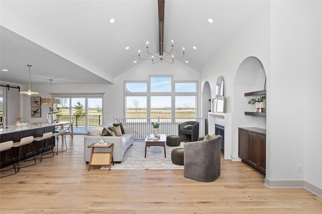 living room featuring an inviting chandelier, high vaulted ceiling, and light wood-type flooring