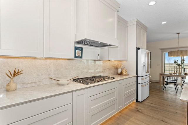 kitchen with stainless steel gas stovetop, light wood-type flooring, high end white refrigerator, backsplash, and pendant lighting