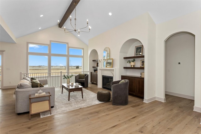 living area featuring a fireplace, high vaulted ceiling, light wood-type flooring, beamed ceiling, and baseboards