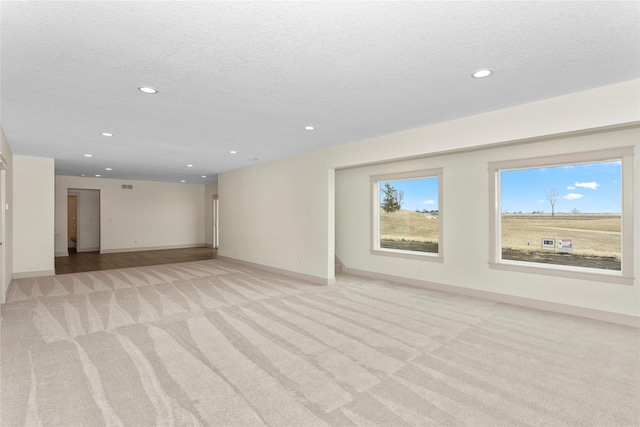 unfurnished room with light carpet, baseboards, a textured ceiling, and recessed lighting