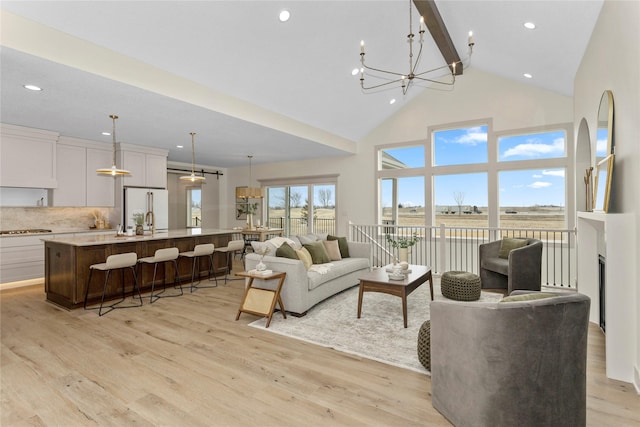 living area featuring high vaulted ceiling, recessed lighting, light wood-style floors, beamed ceiling, and an inviting chandelier