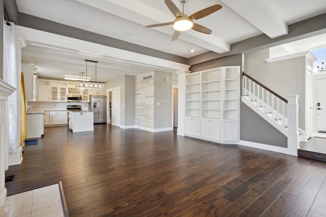 unfurnished living room with beam ceiling, decorative columns, dark hardwood / wood-style flooring, and ceiling fan