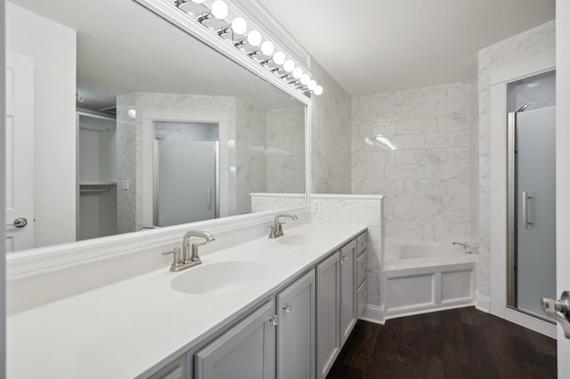 bathroom with vanity, wood-type flooring, a textured ceiling, and plus walk in shower