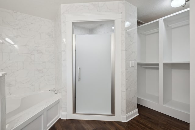 bathroom with plus walk in shower, a textured ceiling, and hardwood / wood-style floors