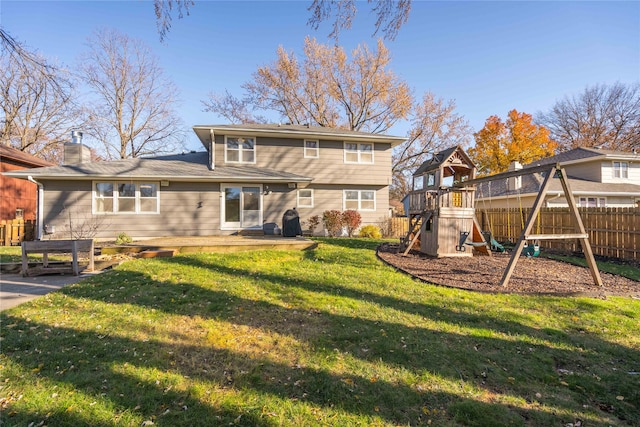 back of house featuring a playground and a lawn