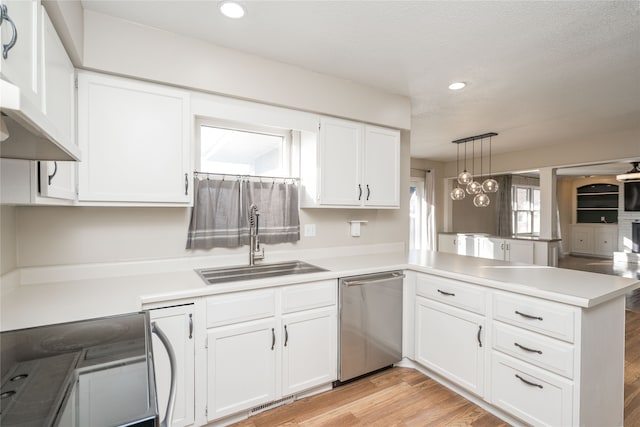 kitchen with sink, stainless steel dishwasher, kitchen peninsula, decorative light fixtures, and white cabinets