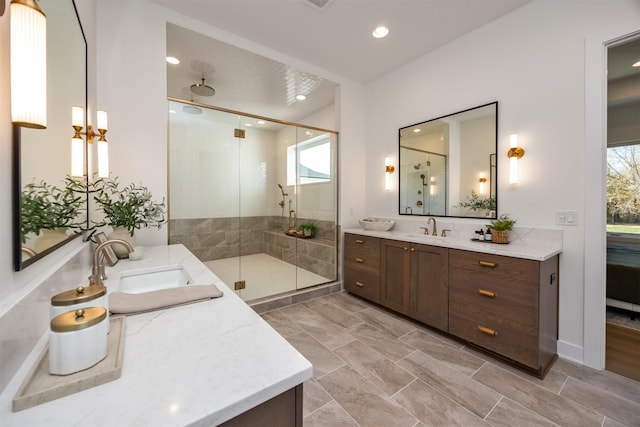 full bathroom featuring a stall shower, two vanities, and a sink