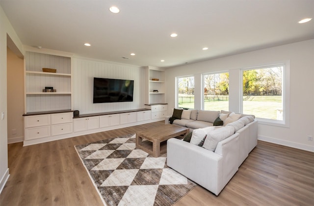 living area with light wood finished floors, recessed lighting, built in shelves, and baseboards