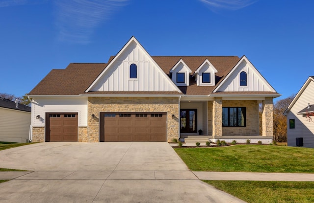 view of front of house with covered porch, french doors, a garage, and a front lawn