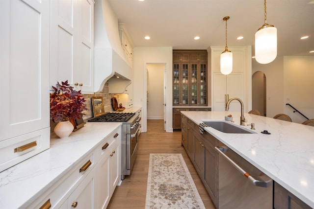 kitchen featuring arched walkways, stainless steel appliances, recessed lighting, tasteful backsplash, and a sink