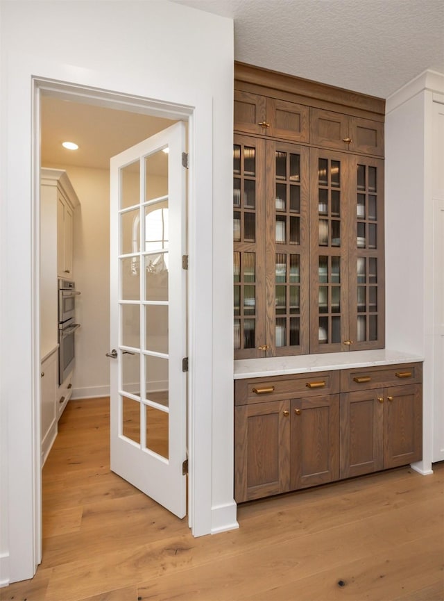 interior space with light wood-style floors, double oven, a textured ceiling, and recessed lighting