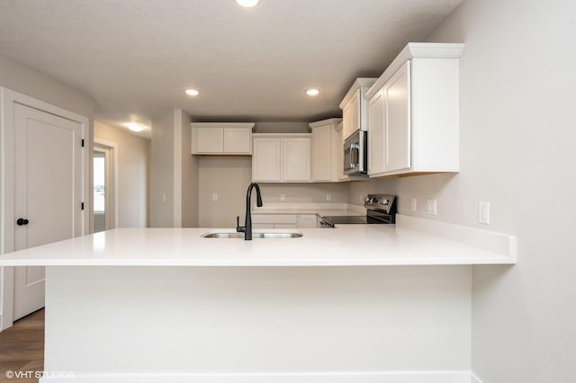 kitchen with white cabinetry, range with electric cooktop, sink, and kitchen peninsula