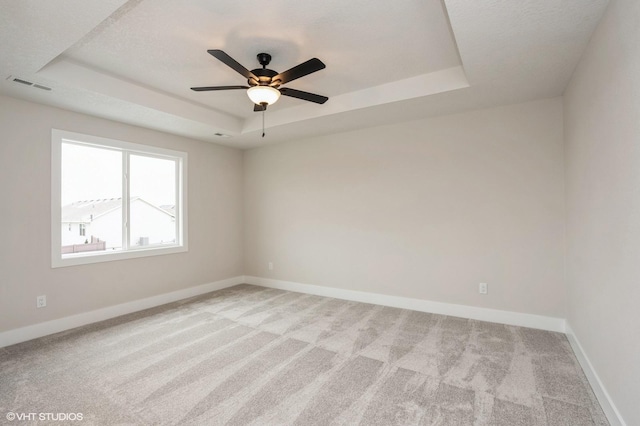 carpeted spare room with ceiling fan and a tray ceiling