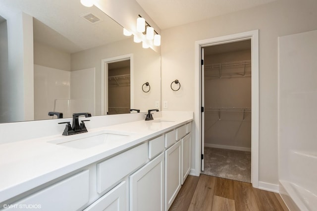 bathroom featuring hardwood / wood-style flooring, vanity, and walk in shower