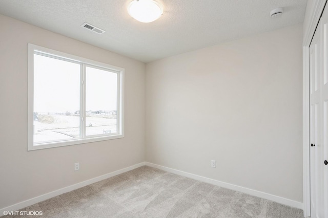 carpeted empty room featuring a textured ceiling