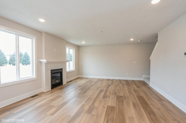 unfurnished living room featuring a wealth of natural light and light hardwood / wood-style flooring