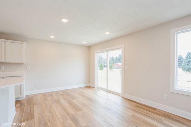 unfurnished living room featuring a textured ceiling and light wood-type flooring