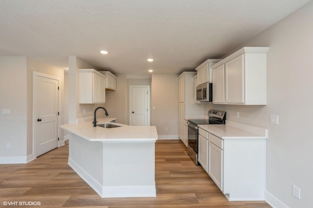 kitchen featuring stainless steel appliances, sink, white cabinets, and light hardwood / wood-style flooring