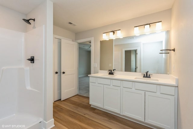 bathroom featuring hardwood / wood-style flooring, vanity, and a shower