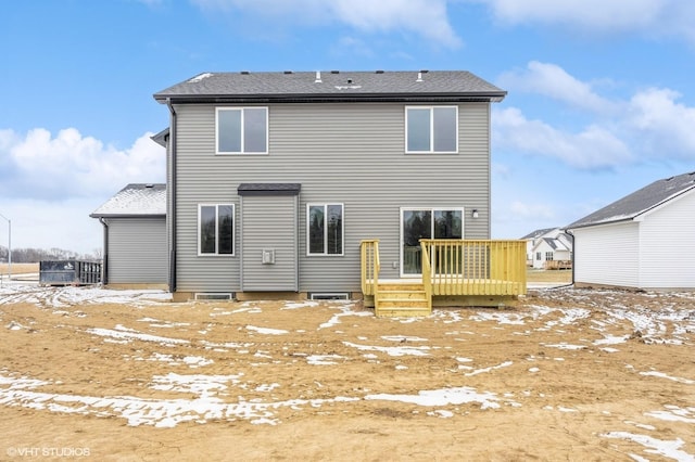 snow covered back of property with a wooden deck