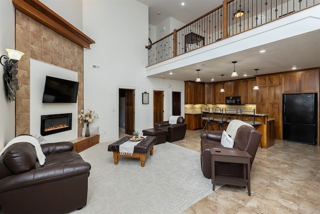 living room with a towering ceiling and a tile fireplace