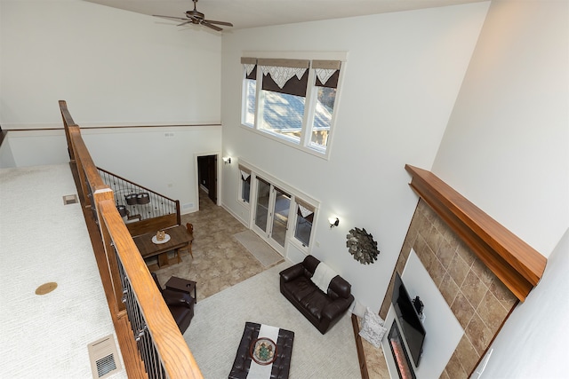 carpeted living room with ceiling fan, a tile fireplace, and vaulted ceiling