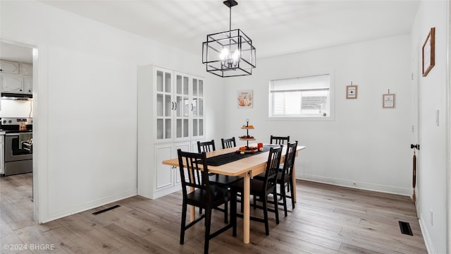 dining room with light hardwood / wood-style floors and an inviting chandelier