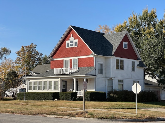 view of front facade featuring a balcony, covered porch, and a front yard