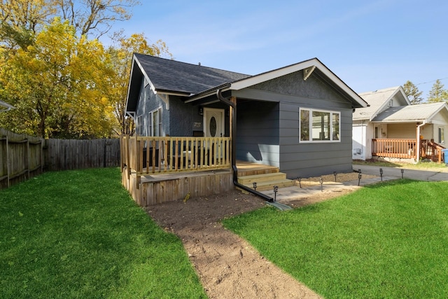 view of front of house with a front lawn, a shingled roof, and fence private yard