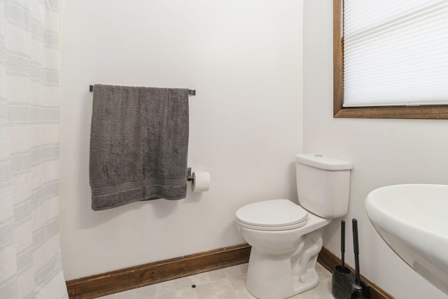 bathroom with a shower with curtain, a sink, toilet, and baseboards