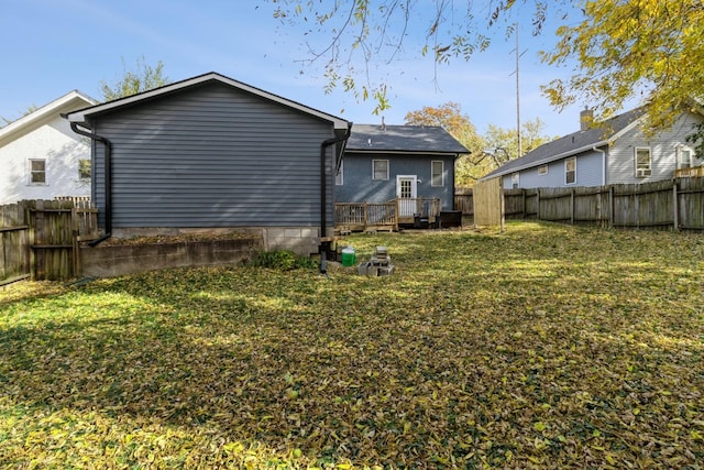 back of house with a fenced backyard, a lawn, and a wooden deck