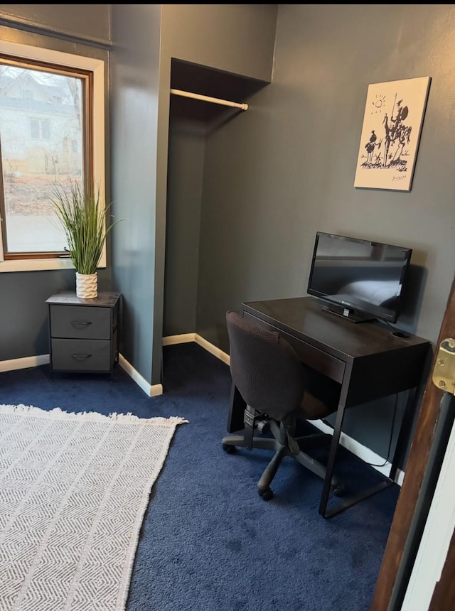 home office with dark carpet and baseboards