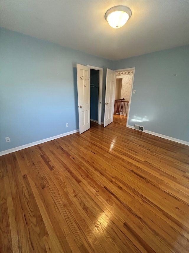 unfurnished bedroom featuring baseboards, a closet, wood finished floors, and visible vents