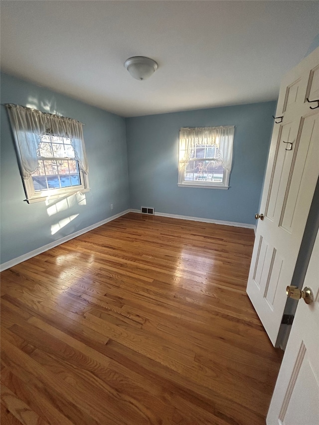 empty room featuring visible vents, baseboards, and wood finished floors
