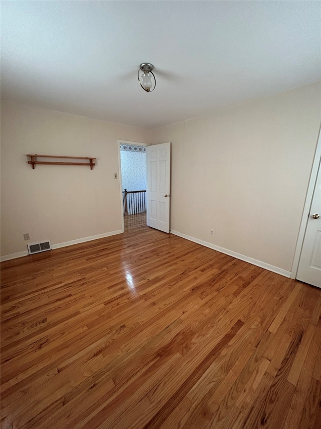 spare room with visible vents, baseboards, and wood finished floors