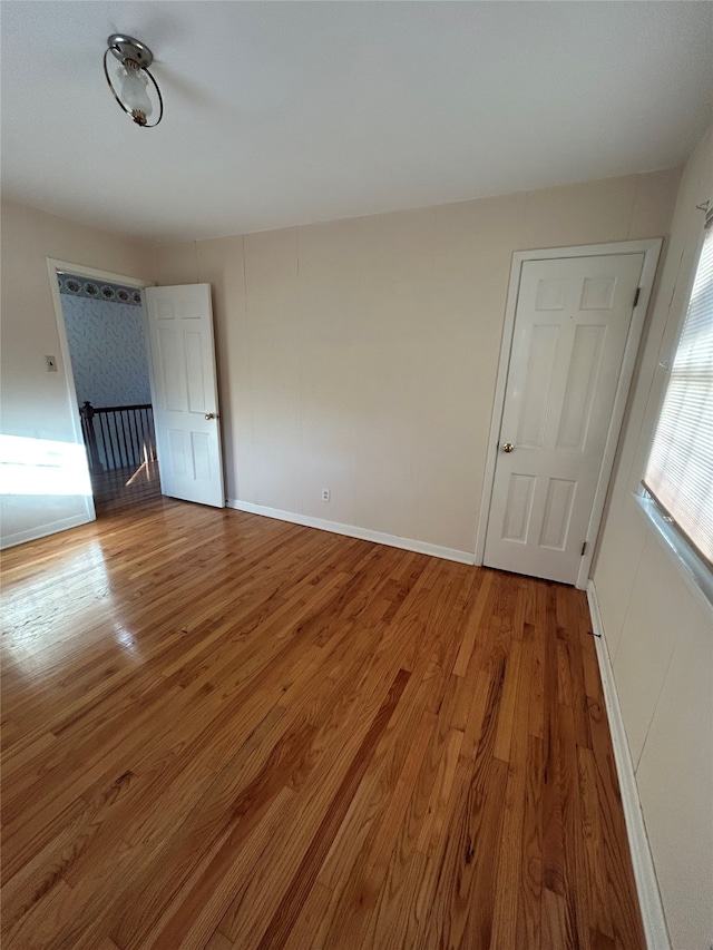 spare room with baseboards and wood finished floors
