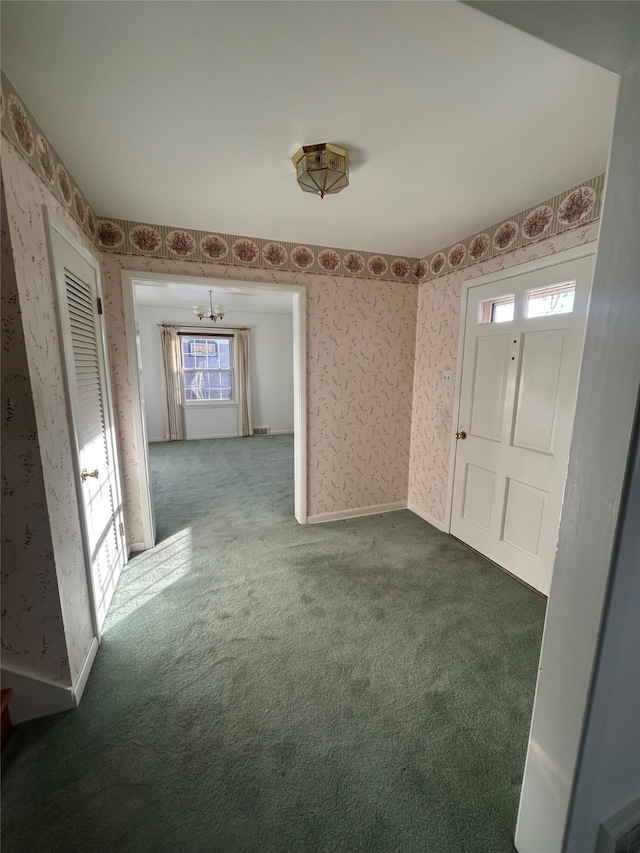 carpeted foyer entrance with wallpapered walls and a notable chandelier