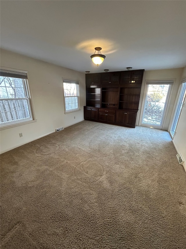 unfurnished living room with carpet floors and visible vents