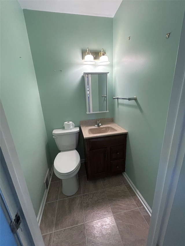 half bath with vanity, baseboards, and toilet