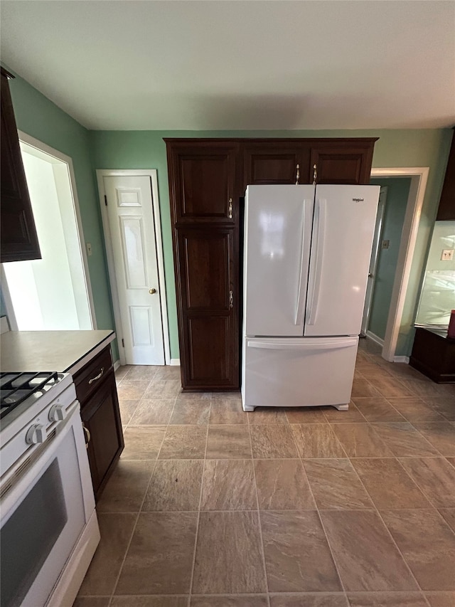 kitchen with baseboards, dark brown cabinets, and white appliances