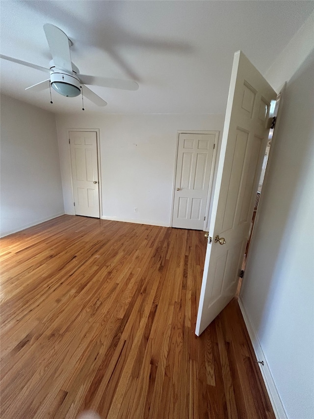 spare room with baseboards, ceiling fan, and wood finished floors