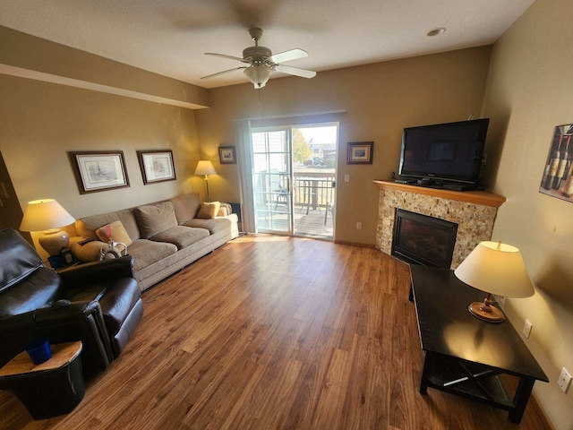 living room featuring wood-type flooring, a fireplace, and ceiling fan