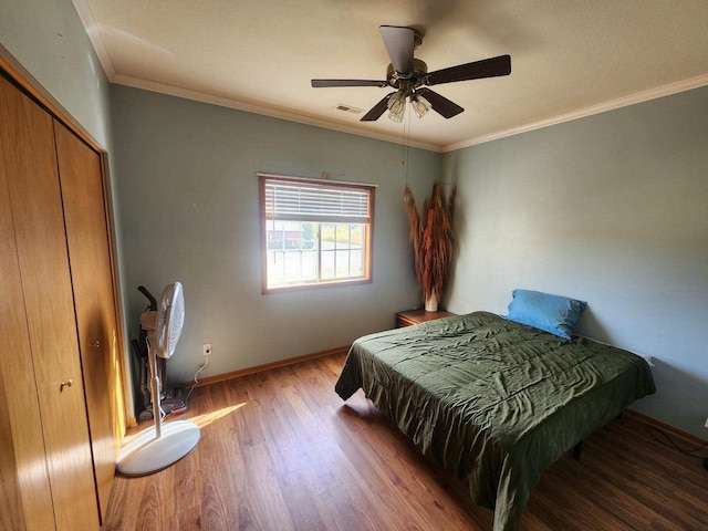 bedroom with dark wood-type flooring, crown molding, a closet, and ceiling fan