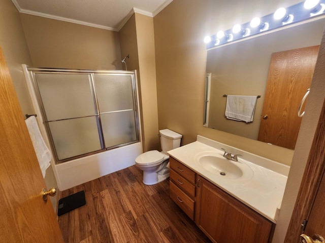 full bathroom featuring enclosed tub / shower combo, hardwood / wood-style flooring, toilet, vanity, and crown molding