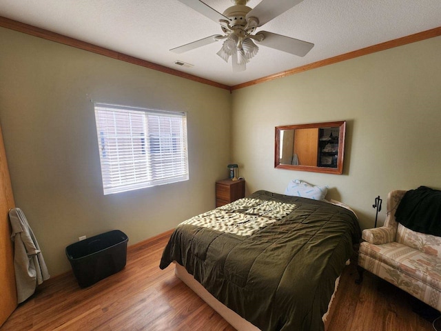 bedroom featuring ornamental molding, a textured ceiling, hardwood / wood-style flooring, and ceiling fan