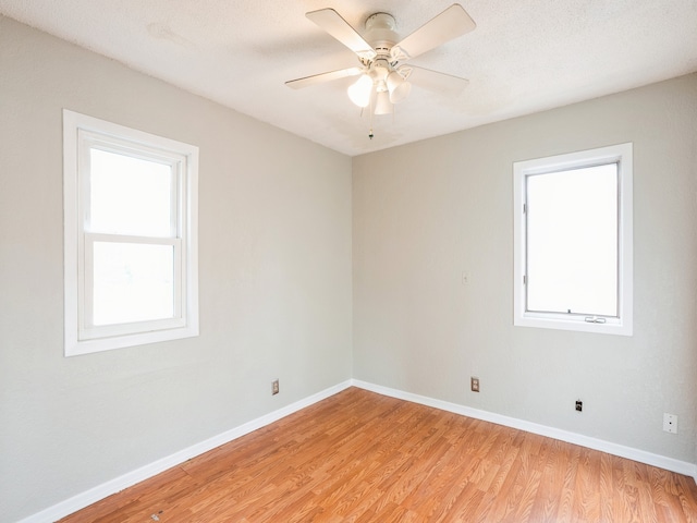 empty room with a textured ceiling, light wood-type flooring, and ceiling fan