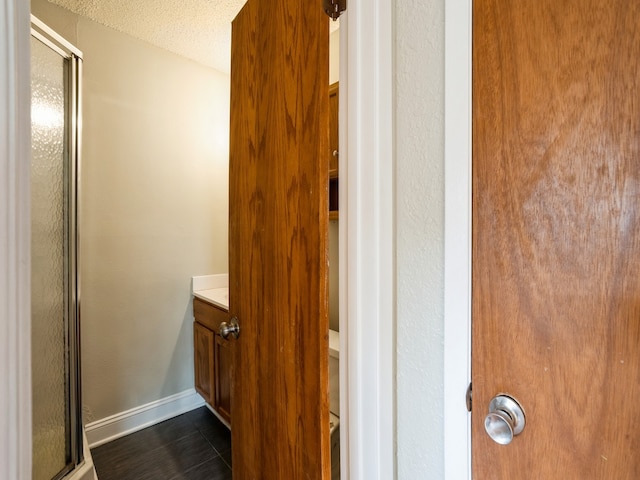 bathroom featuring a shower with door, a textured ceiling, vanity, and tile patterned floors